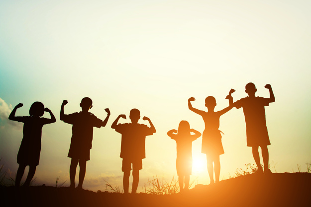 Children silhouettes showing muscles at sunset.